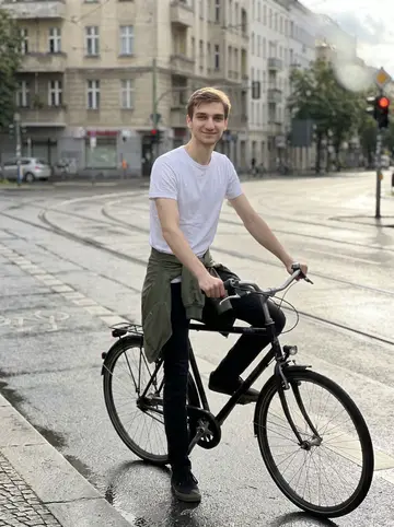Yegor, AI character: a wet Berlin bike lane after summer rain, tram tracks shining in the street