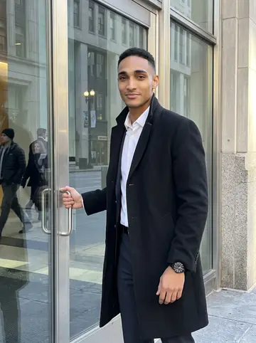 Rome, AI character: outside the LaSalle Street office tower entrance in the Loop, glass doors behind him and pale winter sun…