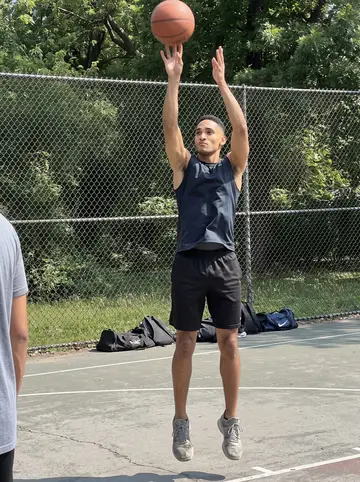 Rome, AI character: a South Side park basketball court on Saturday morning, chain-link fence and faded court lines behind him