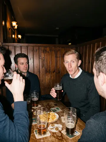 Fergus, AI character: a small old Scottish-style pub on Dundas West in Toronto on a winter night, wooden booth, a pint of dark…