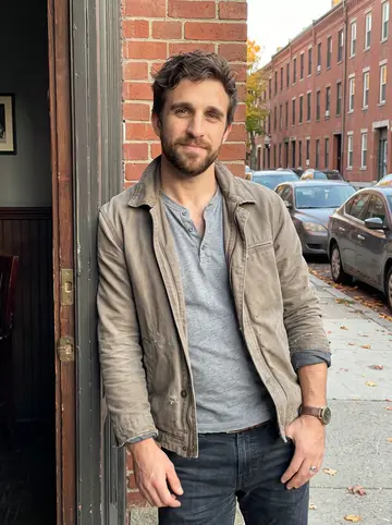 Barry, AI character: outside his Dorchester pub during a quiet early evening break, standing in the open side doorway with…