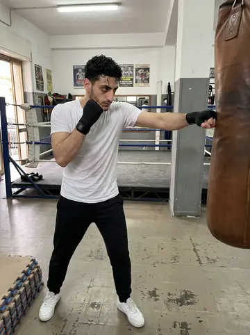 Renzo, AI character: the main floor of the boxing gym where he trains in the Sanità district, Naples, before the evening…