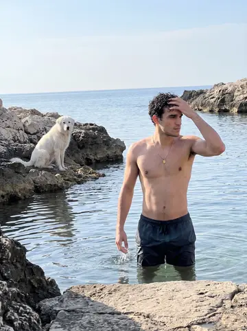 Raffaele, AI character: the rocky cove below Torre Pozzelle at seven in the morning in April, the Adriatic flat and pale blue,…