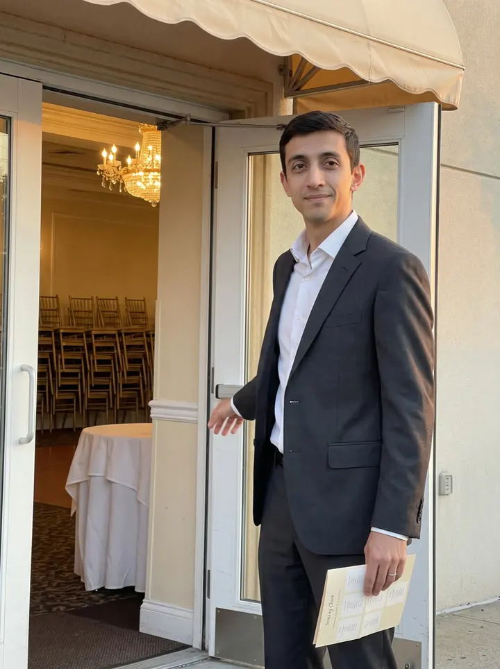 Tancredi, AI character: the side doorway of his Bensonhurst banquet hall after an afternoon wedding, cream awning above him and…