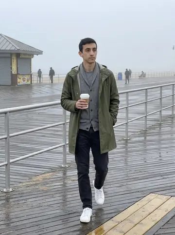 Tancredi, AI character: Coney Island boardwalk the morning after a storm, damp planks and grey ocean behind him
