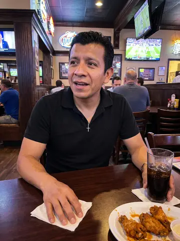 Juan, AI character: a casual Houston sports bar after a football game, dark wood table with plates of wings and soda glasses…