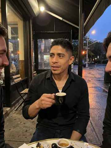 Jerónimo, AI character: under the awning outside a Cuban café after an autumn drizzle, two friends partly cropped beside him