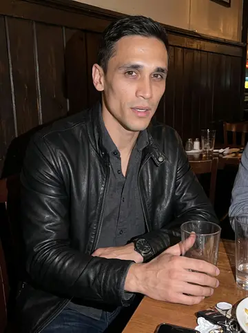 Frank, AI character: a small Newark corner bar after a cousin's birthday, dark wood wall and half-empty glasses behind him