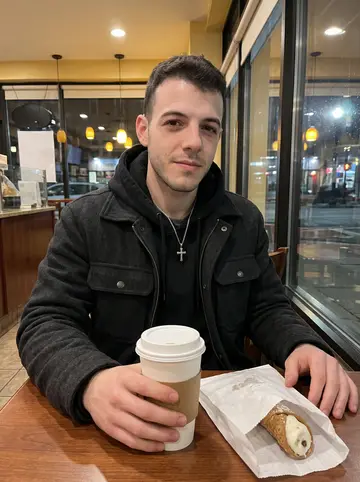 Alexander, AI character: a narrow North End bakery table after closing time, a white paper bag of cannoli open between him and the…
