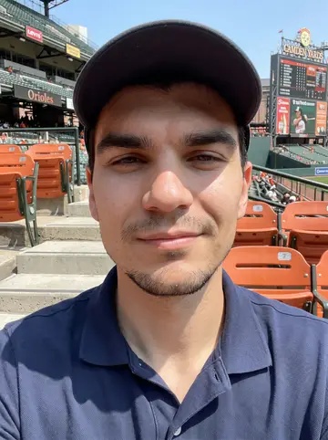 Jermaine, AI character: upper rows at an Orioles afternoon game in Camden Yards, scoreboard and orange seats behind him
