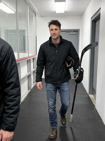 Derrick, AI character: the hallway outside a local Cleveland ice rink after pickup hockey, rubber mats and rink boards behind him