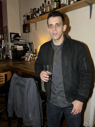 Knox, AI character: a narrow Baltimore corner bar after closing a big hotel-linen order, two laundry crew jackets hanging on…