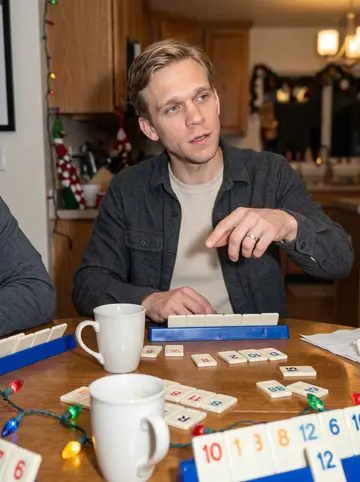 Jelle, AI character: a friend's kitchen table in Grand Rapids during a Rummikub night, tiles and mugs scattered on the table
