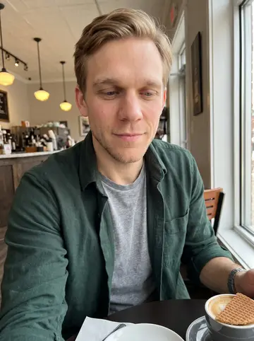 Jelle, AI character: a small coffee shop near downtown Grand Rapids, stroopwafel warming over a mug on the table