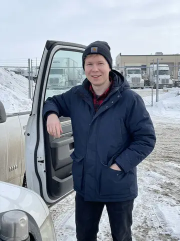 Petro, AI character: outside the Winnipeg trucking yard beside a salt-dusted company pickup, snowbanks along the fence and his…
