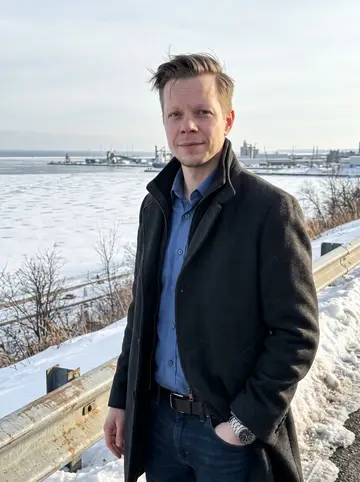 Tommi, AI character: a plowed overlook above Duluth Harbor on a clear cold afternoon, Lake Superior bright behind him