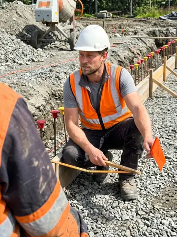 Eirik, AI character: a foundation trench at a building site outside Trondheim, gravel and formwork around him