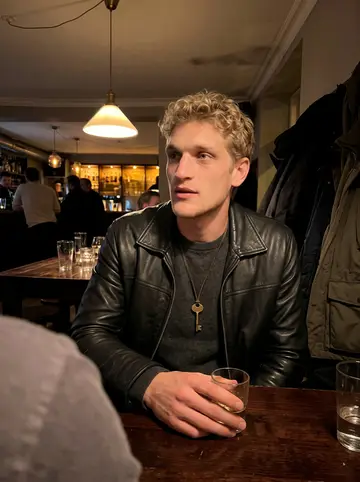 Frederik, AI character: a small Copenhagen beer bar after work, dark wood table, coats piled on a bench, blurred friends cropped…