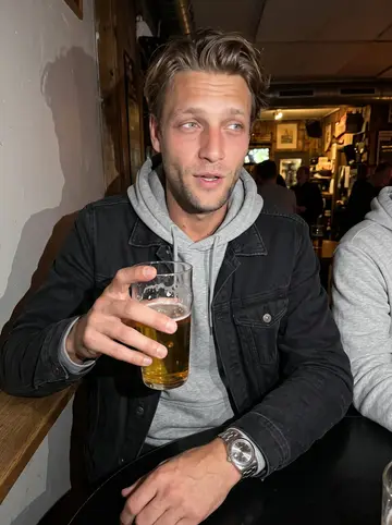Nils, AI character: a small Malmö bar after work, standing at a high table with his younger brother partly cropped beside him