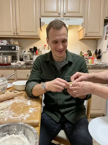 Grigory, AI character: his aunt's small Brooklyn kitchen on Sunday evening, a table dusted with flour and rows of half-folded pelmeni