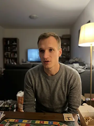 Grigory, AI character: his cousin's living room late at night, Soviet board-game pieces spread across a low coffee table with…
