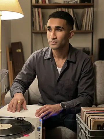 Kojo, AI character: his living room at night beside an old turntable with highlife records stacked on a milk crate