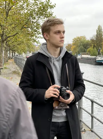Stefan, AI character: the Spree embankment in Moabit, plane trees dropping leaves and a barge moored on the far side