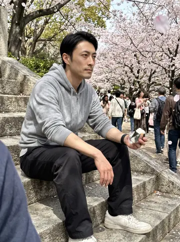Ryu, AI character: stone steps in Osaka Castle park with cherry blossom trees in the background