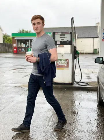 Fergal, AI character: the forecourt of a small garage on the Mallow road just after a shower, wet tarmac and a petrol pump…