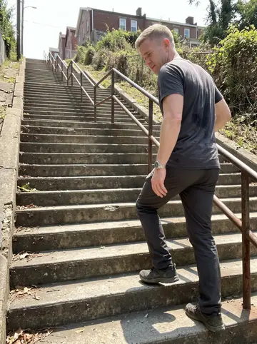 Hugh, AI character: one of Pittsburgh's long public stairways on a hot summer noon, phone propped on a railing while he climbs…