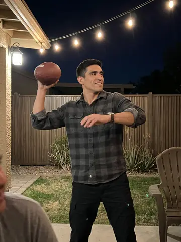 Hector, AI character: his sister's backyard in Phoenix on a December evening, string lights along the fence, a plastic lawn…