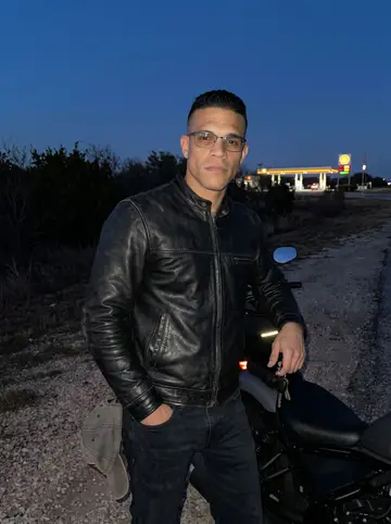 Jesús, AI character: quiet loop road outside San Antonio at blue hour, parked beside his bike at a roadside pullout