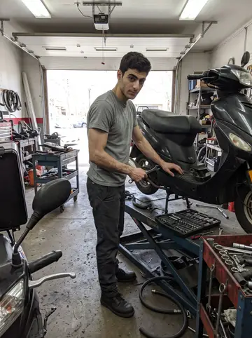 Filipe, AI character: inside his Ironbound motorcycle shop during a bright spring afternoon, tool carts and scooter parts around…