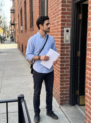 Kimon, AI character: outside a brick apartment building in Astoria while serving papers on a weekday morning