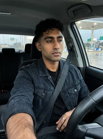 Segun, AI character: parked at a Gulf Freeway gas station after a short rain, wet pavement and pump lights behind the windshield