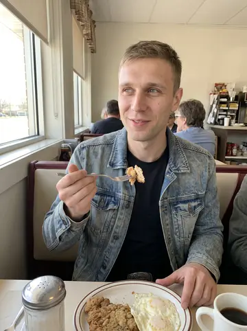 Jesse, AI character: a window booth in a Tulsa diner late on a bright spring morning, chicken-fried steak and eggs on the…