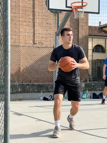 Maurice, AI character: Sunday pickup basketball at an outdoor church court in Parma, chain-link fence and brick wall behind the hoop