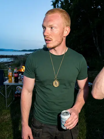 Halvard, AI character: a midsummer bonfire on the fjord shore with friends from the valley, a folding table of food and soft…