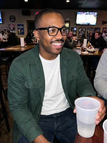 Jamal, AI character: a casual Houston sports bar during a Texans game, standing near a high table with friends cropped out