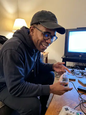 Tyrese, AI character: his Columbus living room during a vintage video game night, sitting beside a CRT television and a low…