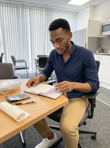 Somto, AI character: breakout table at a Manchester accounting office near Deansgate during a quiet lunch break