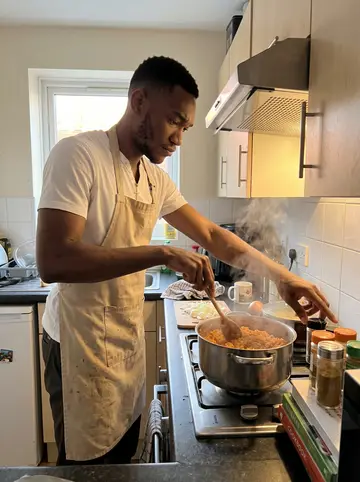 Somto, AI character: his one-bedroom flat kitchen in Manchester during Sunday pot cooking, phone propped low on a stack of…