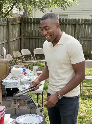 Trevor, AI character: his aunt's backyard in Decatur during a cousin's wedding-prep cookout, folding table and paper plates nearby