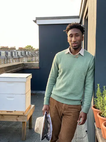 Senyo, AI character: the rooftop of his Croydon apartment building beside the beehive boxes and potted herbs, London flats…