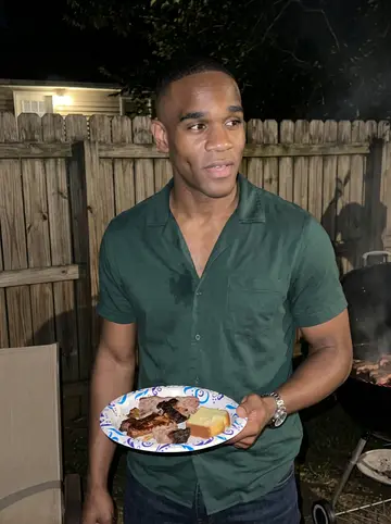 Shaquille, AI character: his grandmother's backyard cookout in southwest Atlanta, folding chairs and a smoking grill behind him