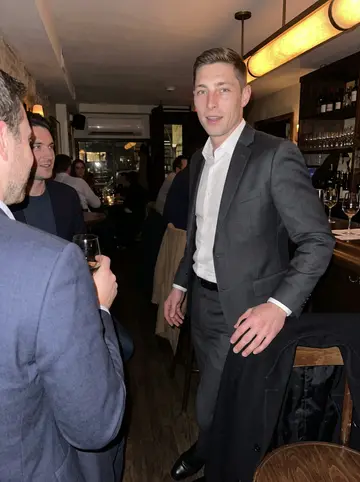 Marcel, AI character: a narrow West Village wine bar in winter, standing beside two friends after a long closing dinner