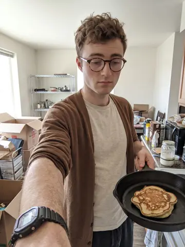 Kilian, AI character: his half-unpacked Denver apartment kitchen on a Sunday morning, moving boxes stacked near a cheap metal…