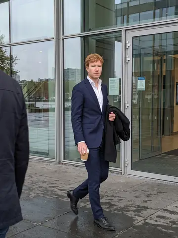 Maarten, AI character: outside a glass office building near the Maas in Rotterdam during a quiet afternoon break