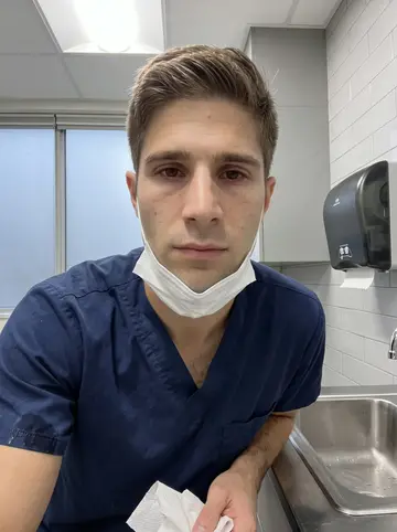 Niklas, AI character: a clean veterinary exam room in his Boston clinic, stainless exam table, cabinets, folded towels and a…