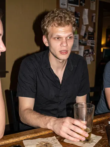 Rens, AI character: low-key Austin neighborhood bar with two coworkers partly cropped at the edge